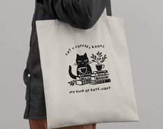 a person holding a tote bag with an image of a cat and coffee books on it