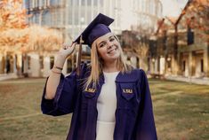 a woman wearing a graduation cap and gown in front of a building with tall windows