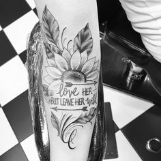 a black and white photo of a woman's leg with a sunflower tattoo on it