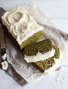 a loaf of green tea cake with cream cheese frosting on top and two slices cut off