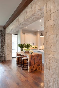 an open kitchen and living room with wood flooring on the walls, along with wooden stools