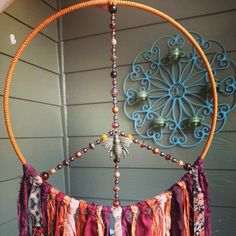 an orange and pink dream catcher hanging on the side of a house next to a wall