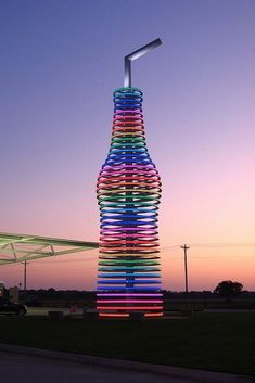 a tall tower made out of plastic tubes in the middle of a field at dusk