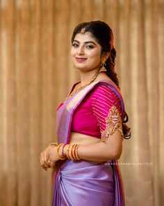 a woman wearing a purple sari and gold jewelry