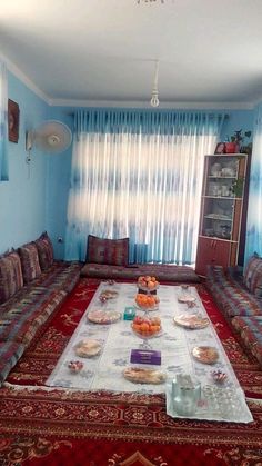 a living room filled with lots of couches and plates on top of a rug