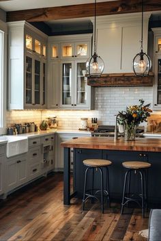 a large kitchen with wooden floors and gray cabinets, two stools at the island