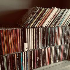 a collection of cds sitting on top of a shelf next to each other in a room