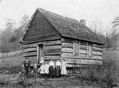 an old black and white photo of people in front of a log cabin