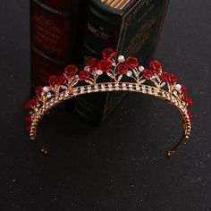 a tiara with red roses and pearls on the side, sitting next to an open book