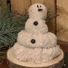 a snowman made out of wood sitting on top of a wooden stump next to a pine tree