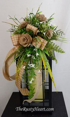 a vase filled with flowers and greenery on top of a table