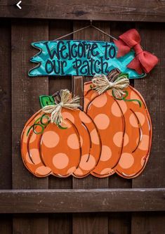 a welcome to our patch sign hanging on a wooden fence with polka dot pumpkins