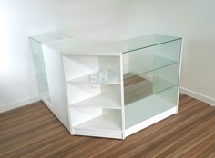 an empty white shelf with glass shelves on the bottom and wood flooring in front of it