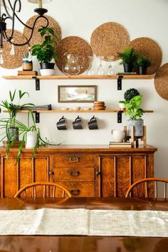 a dining room table with some plants on top of it and shelves above the table