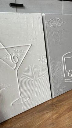 two white wall panels with an image of a cocktail glass on them and the bottom one has a drawing of a martini in it