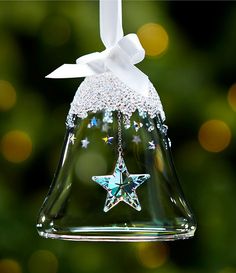 a glass bell ornament with a star hanging from it's side and a white bow on top