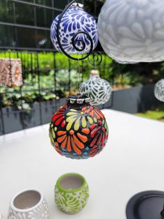 colorful glass ornaments hanging from the ceiling above a table with cups and saucers on it