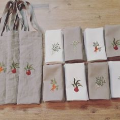 napkins with embroidered vegetables on them laid out on a wooden table next to a bag