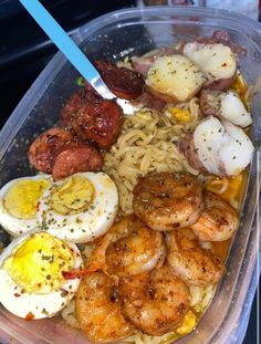 a plastic container filled with pasta, shrimp and eggs on top of it's side