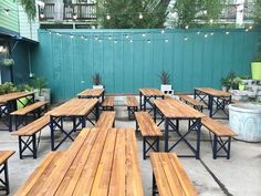 tables and benches are lined up outside on the concrete floor in front of a green wall