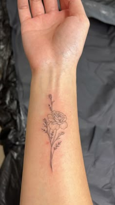 a woman's arm with a flower tattoo on the left side of her wrist