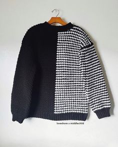 a black and white sweater hanging on a wooden hanger