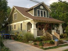 the house is painted green and has white trim on the front door, windows, and porch