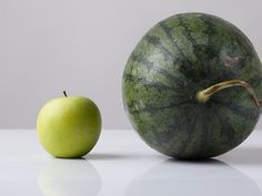 an apple and a watermelon sitting side by side