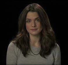 a woman with long brown hair is looking at the camera