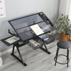 an office desk with a glass top and black metal legs is shown in front of a gray wall