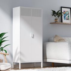 a white cabinet sitting next to a couch and potted plant in a living room