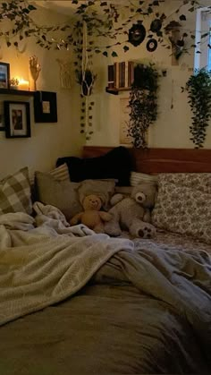 a bed with stuffed animals on it in a room filled with plants and hanging pictures