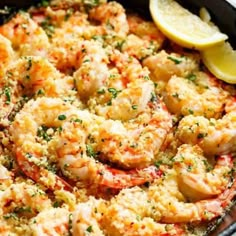 a close up of a plate of food with shrimp and lemons on the side