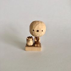 a small wooden figurine with an animal on it's head and another toy in the foreground