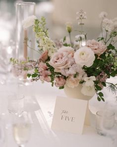 a vase filled with lots of flowers on top of a white tablecloth covered table