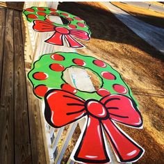 three christmas wreaths painted on the side of a wooden fence with red and green bows