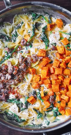 pasta with sausage, spinach and cheese in a pan on a wooden table top