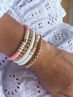 Are you searching for the trendy pink beaded boho bracelets to elevate your accessory game? Look no further! Our stack of 5 bracelets offers versatility and endless possibilities, allowing you to mix and match to your preference. Whether you're aiming for a layered and trendy look or a single statement piece, these bracelets have got you covered. Check out our beautiful stack of 5 beaded stretch bracelets for women, made with real gold plated beads, pink and white heishi beads. Handcrafted with love and a keen attention to detail, our beaded boho bracelets are designed to exceed your expectations. Crafted with high-quality materials, these bracelets capture the essence of bohemian style, perfect for those seeking a free-spirited, artsy vibe. The golden beads boast a touch of elegance and o Heishi Bead Bracelet Patterns, Pink Beaded Bracelet, Pink Beaded Bracelets, Bracelet Trendy, Beach Bracelet, Beach Bracelets, Jewelry Summer, Clay Bracelet, Bracelets Set