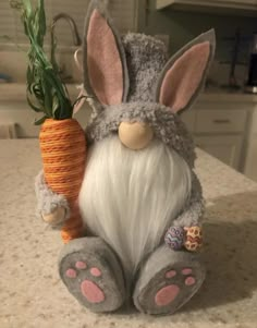 a stuffed rabbit holding a carrot on top of a counter