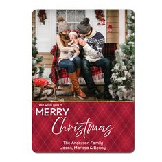 a merry christmas card with an image of two people sitting on a bench in front of a house