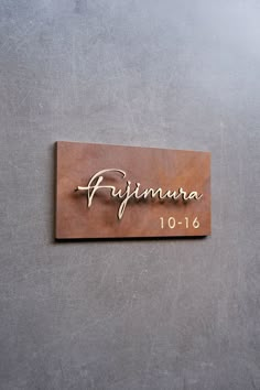 a wooden sign that says primara on the side of a gray wall with gold lettering