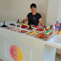 a woman standing behind a buffet table filled with different types of foods and drinks on it