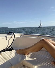 a woman sitting on the back of a boat in the ocean with her feet propped up