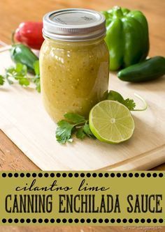 a jar filled with green sauce sitting on top of a cutting board next to peppers