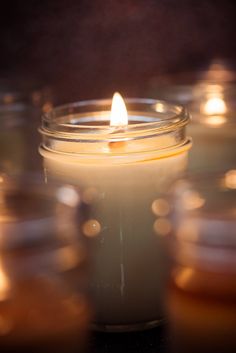 several lit candles are sitting in rows on a table with blurry lights around them