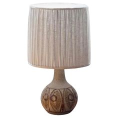 a table lamp with a beige shade on it's base and a white pleated lampshade