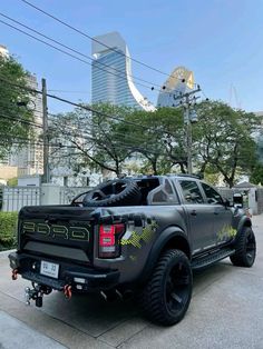 the truck is parked on the side of the road in front of some trees and buildings