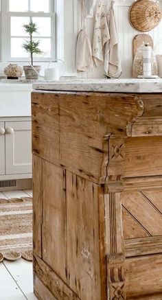 an old wooden cabinet in a white kitchen with lots of natural materials on the counter