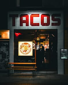 a man standing in front of a building with a sign that reads taco's