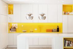 a kitchen with white cabinets and yellow lighting on the countertop, along with bookshelves